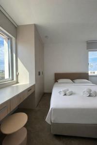 a white bedroom with a bed and a window at Terra Rossa Residences in Paralimni
