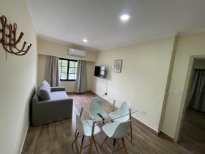 a living room with a glass table and white chairs at El Viejo Albergue in Luján