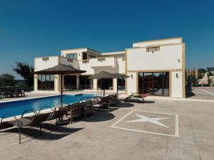 a building with a swimming pool with chairs and umbrellas at RyadIbou in Essaouira