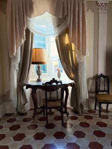 a room with a table and a window with a lamp at Palazzo Lari Sarzana - Historic Boutique Rooms in Sarzana