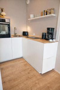 a kitchen with white cabinets and a wooden floor at Strandhafer-Balkon mit Meerblick- 2 Min zum Strand in Schausende +11 photos