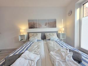 two beds sitting next to each other in a bedroom at Ferienwohnung NordTroll in Norden