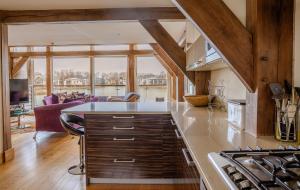 a kitchen with wooden ceilings and a large kitchen island at Lakeside Cotswolds Retreat with Private Hot Tub set on Lower Mill Estate in Somerford Keynes