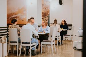 a group of people sitting around a table in a restaurant at Hotel O3zone - Mountain Spa & Conference in Băile Tuşnad
