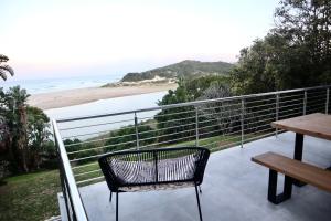 a balcony with a bench and a view of the beach at Chintsa Oceanfront in Chintsa