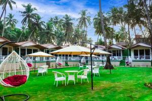 a resort with tables and chairs and palm trees at Agonda Junction in Agonda