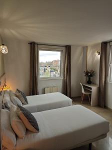 a hotel room with two beds and a window at Hostal Fronton in Alcobendas