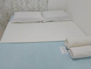 a bed with white sheets and pillows on it at Zoldyck Property in Pahanocoy