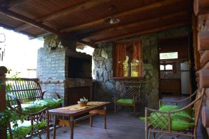 a porch with a table and chairs and a stone fireplace at Cabañas "La Quimera" in El Durazno