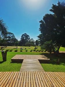 a wooden walkway in a park with trees and grass at Pontal Tapes Hotel in Tapes