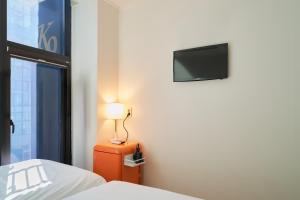 a bedroom with a bed and a television on a wall at K9 Myeongdong Hotel in Seoul