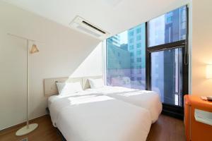 a white bed in a room with a large window at K9 Myeongdong Hotel in Seoul