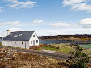a white house on a hill with a body of water at 4 Bed in Scourie oc-ca399 in Scourie