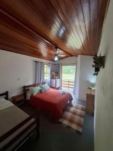 a bedroom with a red bed and a wooden ceiling at Pousada Vitoria in Gonçalves