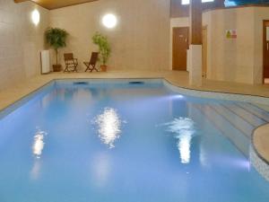 a large swimming pool with blue water in a building at Finest Retreats - Little Dunley - Lake View in Bovey Tracey