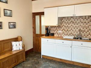 a kitchen with white cabinets and a bench in it at Fiona's House in Filey +8 photos