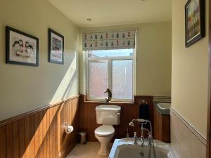 a bathroom with a toilet and a sink and a window at Fiona's House in Filey