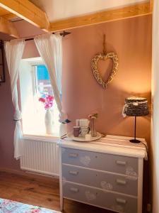 a room with a dresser and a heart mirror on the wall at Skrattande Ko in Tingsryd