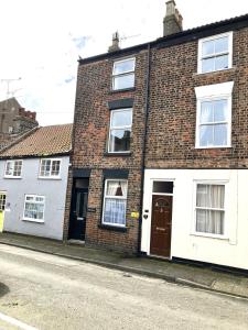 a brick house with white doors on a street at Fiona's House in Filey