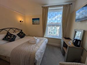 a bedroom with a bed and a desk and a window at Del Mar in Llandudno