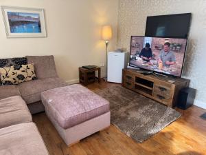 a living room with a couch and a flat screen tv at The Penthouse- The Kingsley Collection in Troon