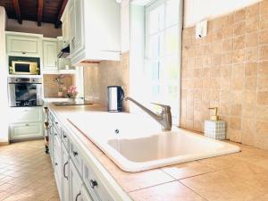 a white kitchen with a sink and a window at La Longère au Fil des Saisons in Favières