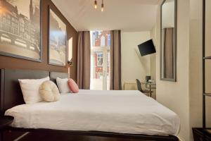 a bedroom with a large white bed with a window at Quentin Museum Square Hotel in Amsterdam