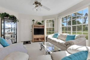 a living room with couches and a tv and windows at 4111 Gunnison Ct #1214 in Estero