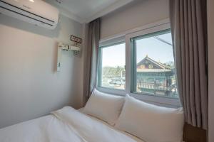 a bed with pillows in a room with a window at KIMSTEL Jongno in Seoul