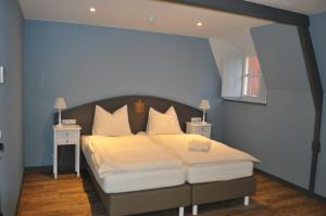 een slaapkamer met een groot bed met witte lakens en kussens bij Kasteel Aldenghoor in Haelen