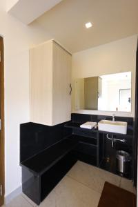 a black bathroom with a sink and a mirror at Hotel Rock Port Inn in Rushikonda