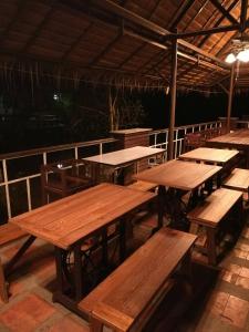 een groep houten tafels en banken op een dek bij Young Coconut Garden Home Resort in Amphawa