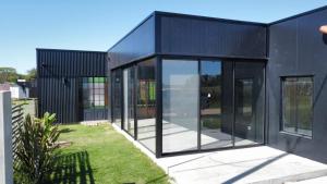 a black house with glass doors and a yard at La Su in Duggan