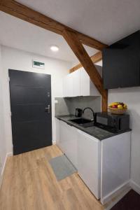 a kitchen with a sink and a black door at Apartamenty Stary Młyn in Wronki