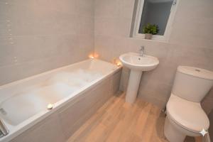 a bathroom with a tub and a toilet and a sink at Fossgate Luxury Duplex City Centre Apartment with Free Parking in York