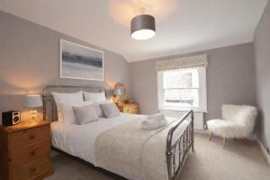 a bedroom with a bed and a chair and a window at Fossgate Luxury Duplex City Centre Apartment with Free Parking in York