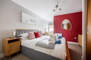 a bedroom with a large bed with a red wall at Seafarers - Contemporary Apartment, Central Location in Poole