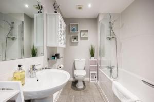 a white bathroom with a sink and a toilet at Seafarers - Contemporary Apartment, Central Location in Poole