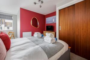a bedroom with red walls and a bed with towels at Seafarers - Contemporary Apartment, Central Location in Poole