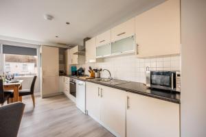 a kitchen with white cabinets and a table and a counter at Seafarers - Contemporary Apartment, Central Location in Poole +23 photos