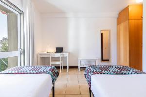 a bedroom with two beds and a desk and a window at HI Guarda - Pousada de Juventude in Guarda