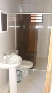 a white bathroom with a toilet and a sink at Casa de Trindade-Go in Trindade