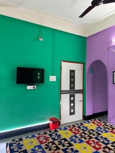 a room with green and purple walls and a tv at Zen Garden Homestay in Jorhat