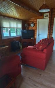 a living room with a red couch and a tv at Hamishs log cabin in Blaenau-Ffestiniog