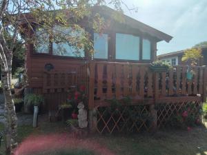 a tiny house with a fence and a tree at Hamishs log cabin in Blaenau-Ffestiniog