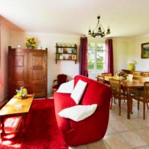a living room with a red chair and a table at La maison de Dourils in Entraygues-sur-Truyère