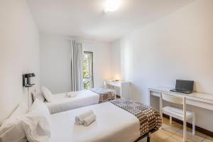 a bedroom with two beds and a desk with a laptop at HI Guarda - Pousada de Juventude in Guarda +27 photos