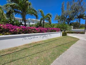a sign in front of a garden with pink flowers at 102 Lighthouse Bay Barbados in Christ Church