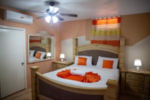 a bedroom with a bed with an orange blanket on it at Master Universel Hotel Bar Restaurant in Cap-Haïtien