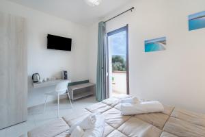 a white bedroom with a large bed and a desk at Via del Mare in Giba